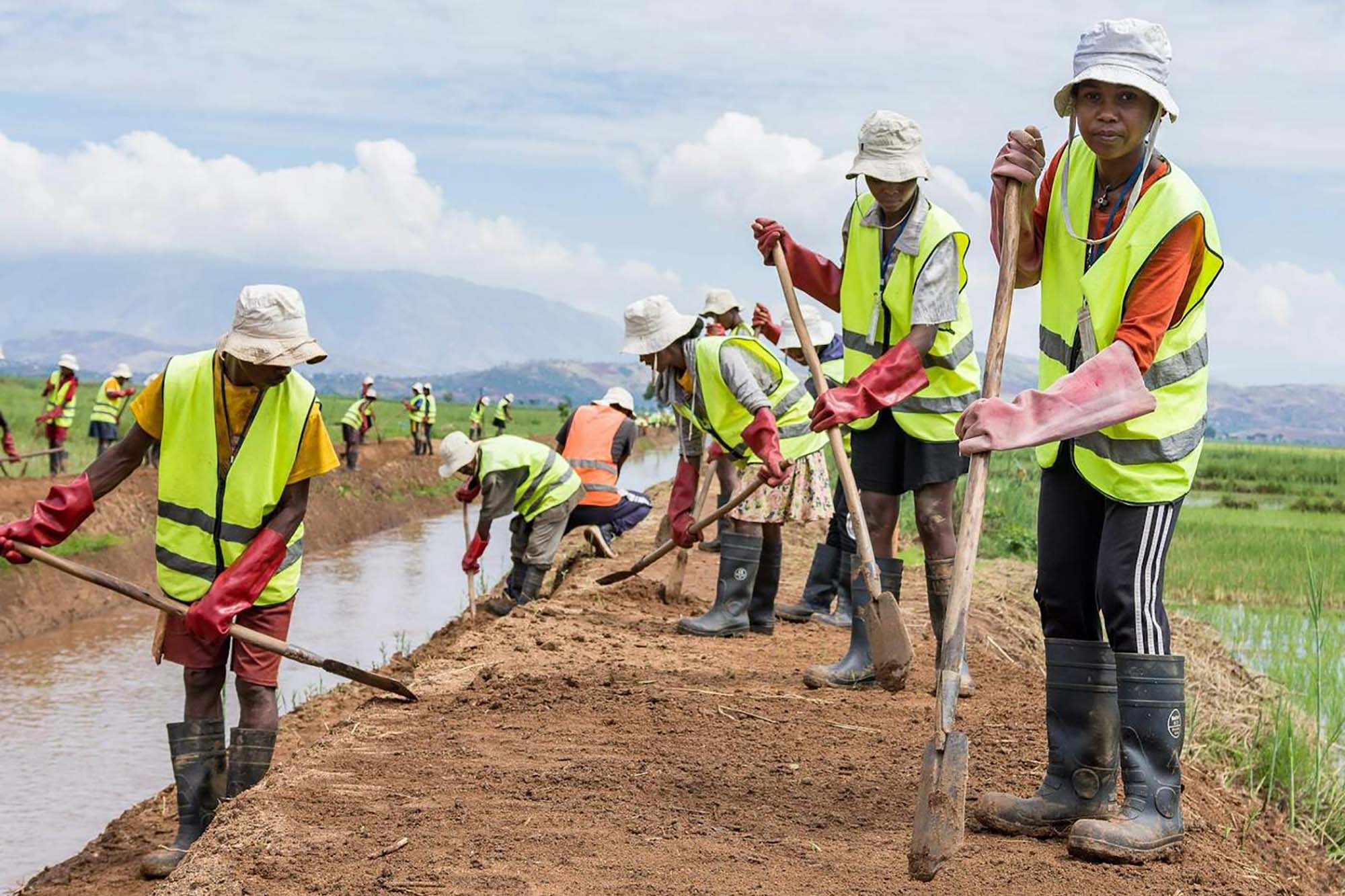 A group of workers engaged in manual labor along a canal. 