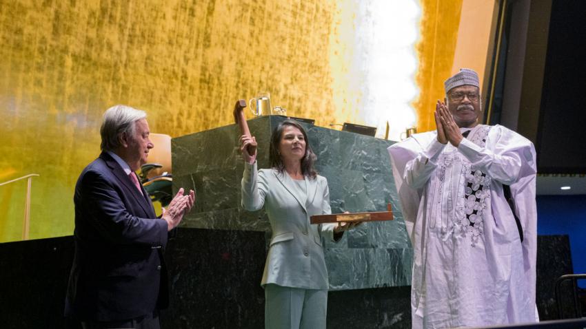 Annalena, flanked by the UNSG and former PGA, holds up the gavel in the UN General Assembly hall.
