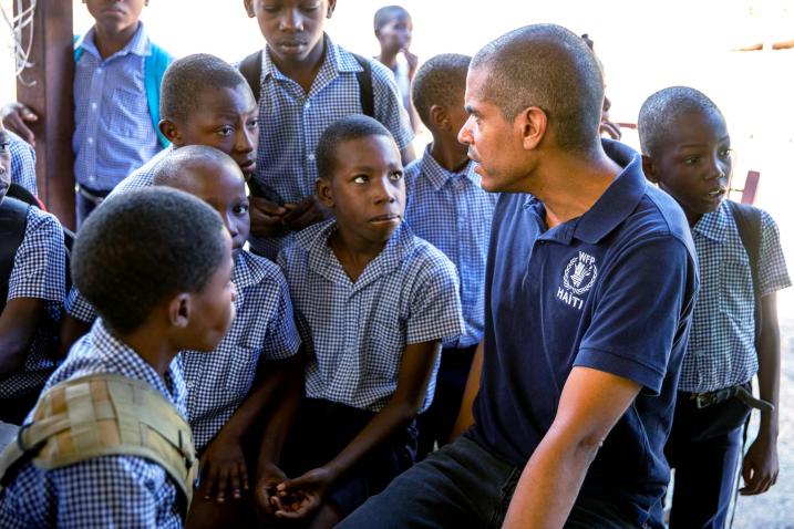 Jean-Martin sitting amongst students dressed in school uniforms is chatting with them