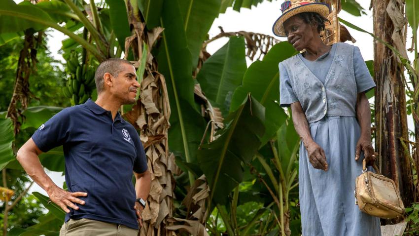 Jean-Martin is in the outdoors and facing a woman who is dressed up with a straw hat