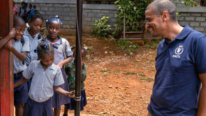 Jean-Martin looks on school children standing in a group to his right