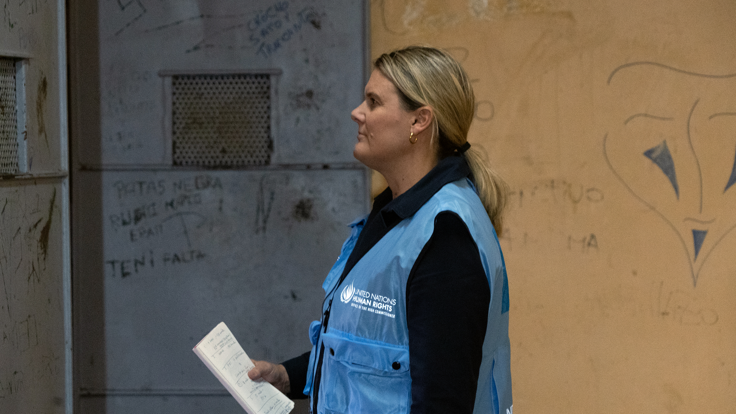 Alice holds a notebook while she observes an indoor space