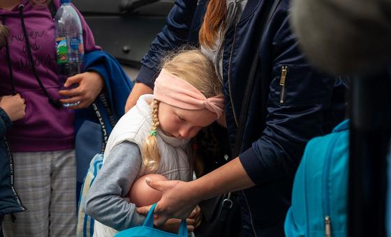 A five-year-old girl is comforted by her mother as she waits  in Zaporizhzhia to board a bus to Poland.