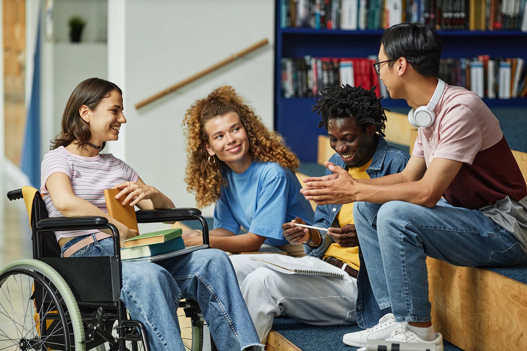 A diverse group of young people chatting in a college library.