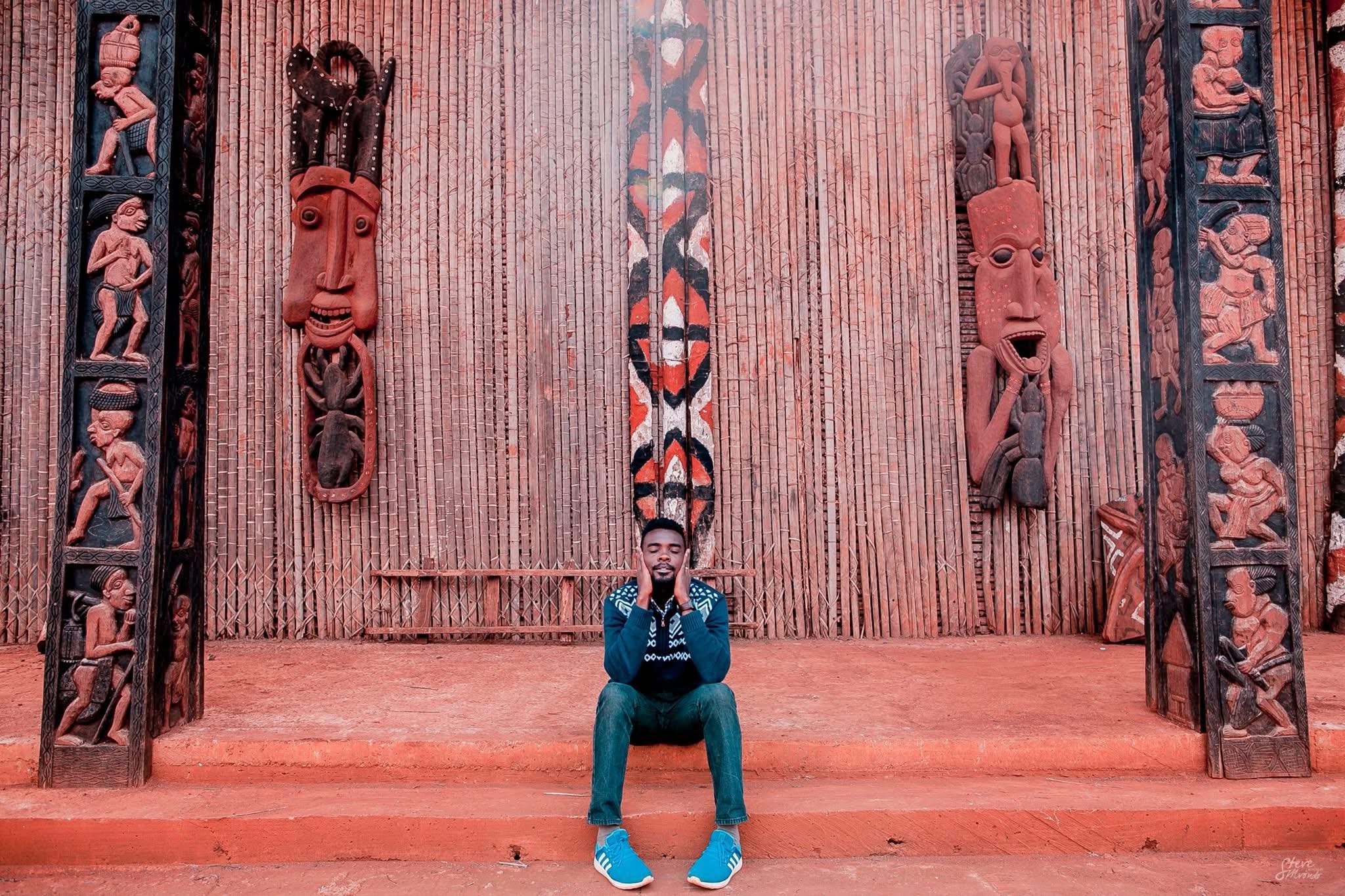 Steve Biko sitting in a room surrounded by cultural artifacts.