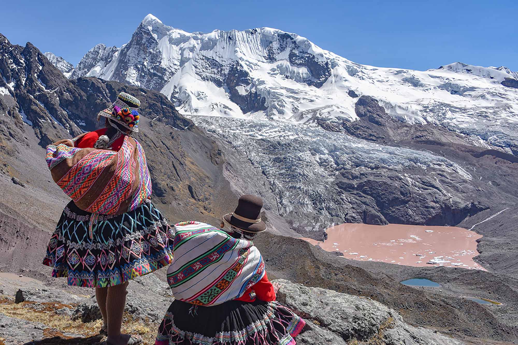 Two Quechua women admire the views of the Andean mountains on the Ausungate trail. Cusco, Peru.