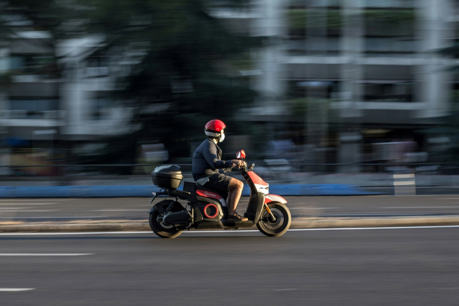 A speeding delivery man on a motorbike.