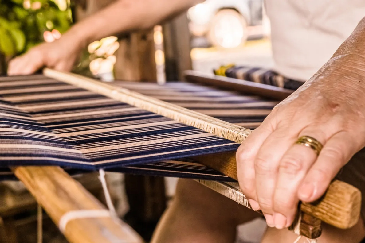 A picture of a hand at a weaving station.