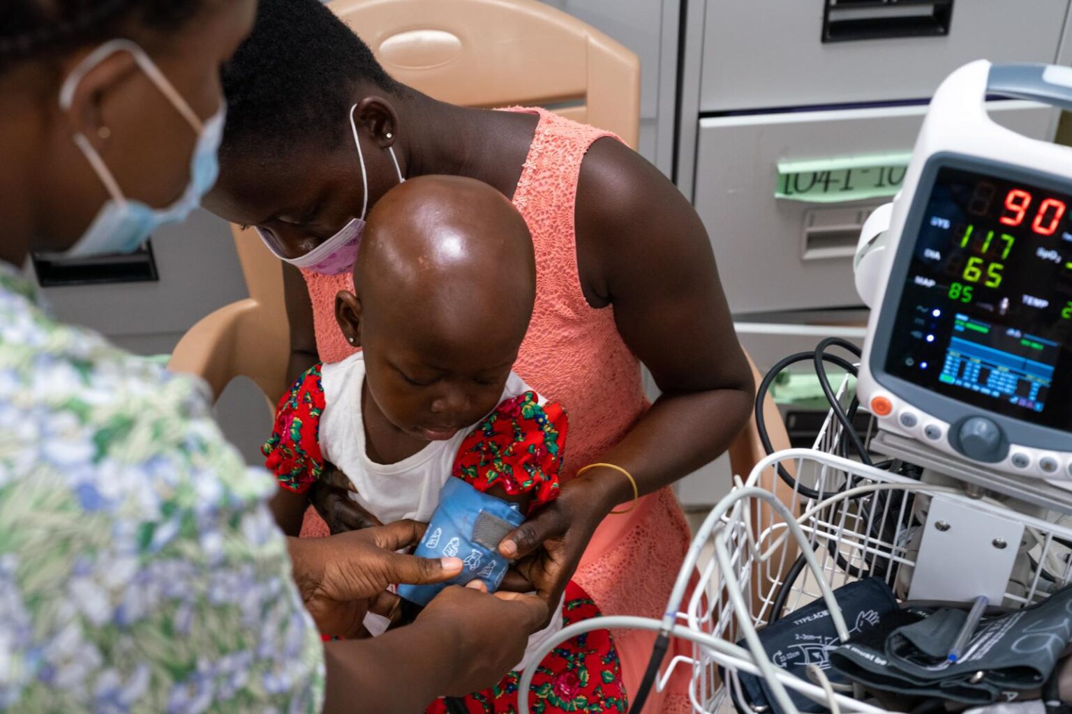 A doctor examines a young child sitting on his mother's lap.