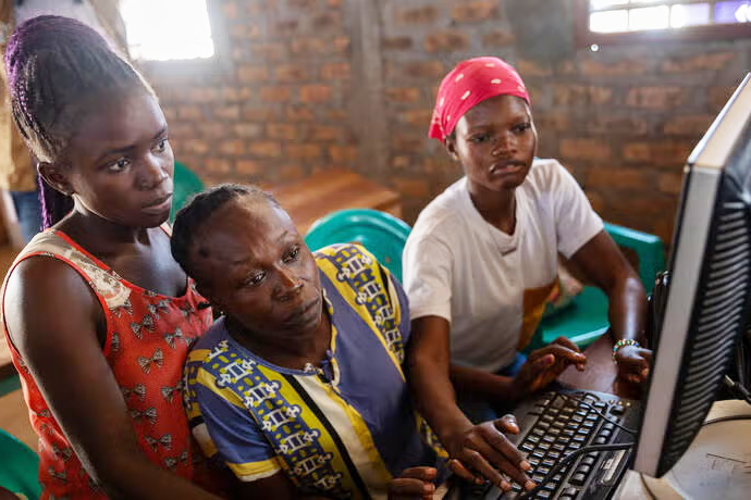 Three women at a computer station.